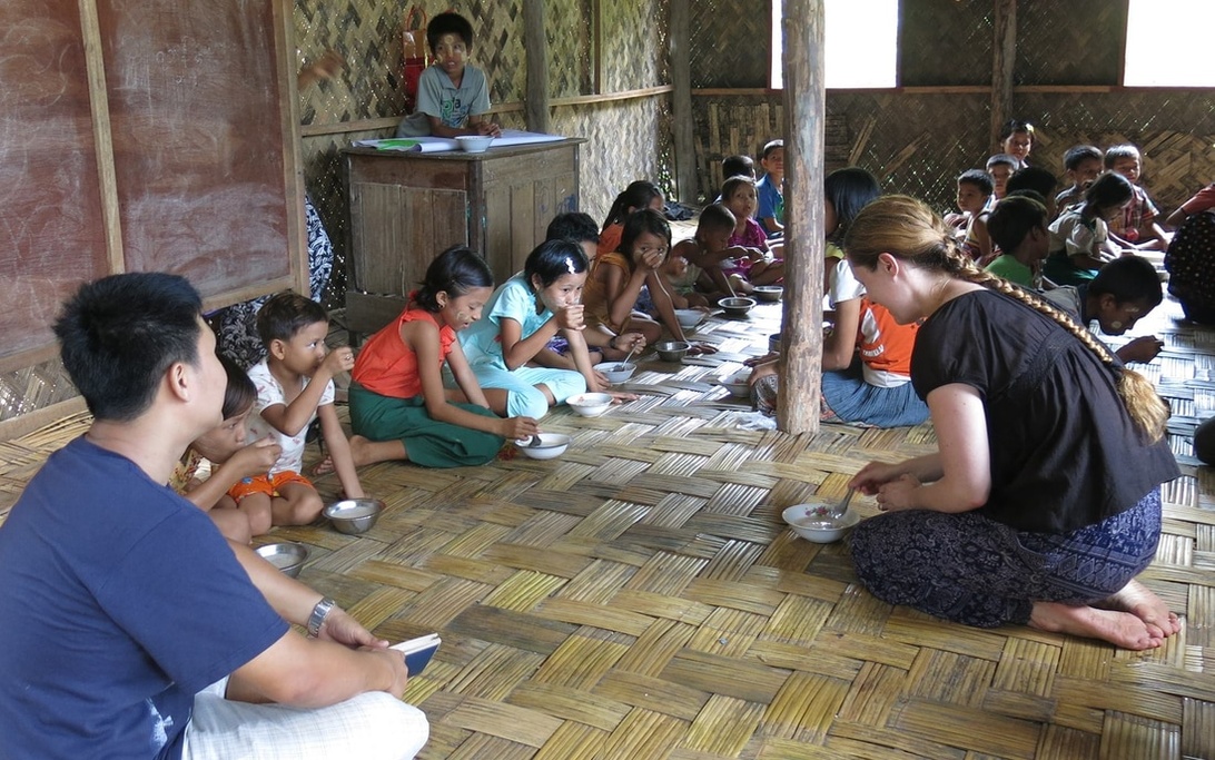Adults and children share a meal in a community setting, highlighting the collaborative and supportive work of a nonprofit program.